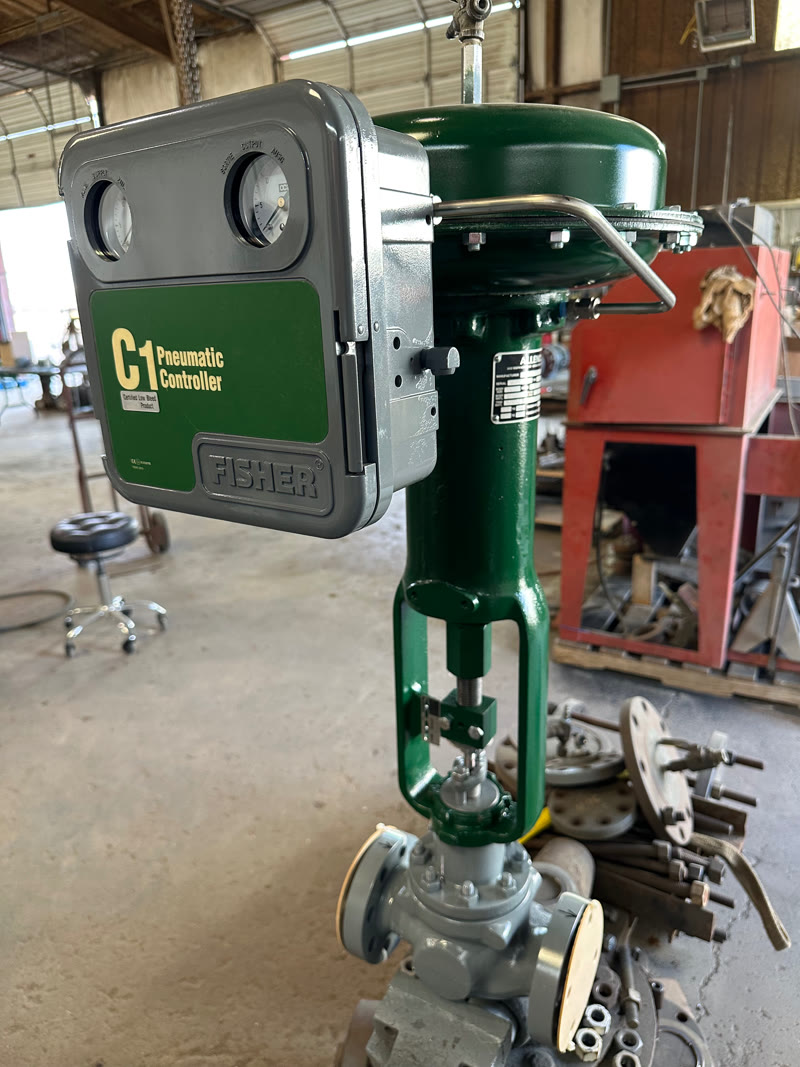 Fisher C1 pneumatic controller mounted on a green valve actuator in the shop